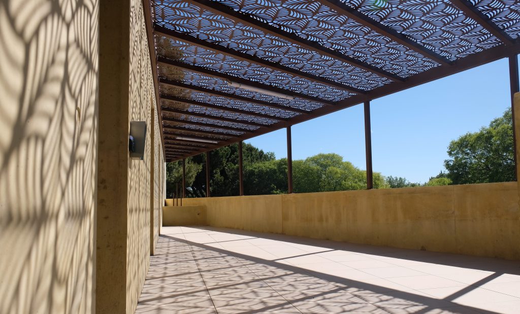 Terrasse Sud ombragée par une structure ajourée, prolongement des salons de veillée du complexe funéraire de Grammont.